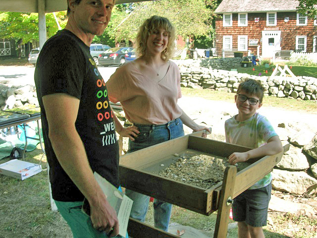 October 5, 2024. Krista Dotzel and an unidentified volunteer demonstrate the 
                                       finer points of screening to a young archaeologist-to-be.