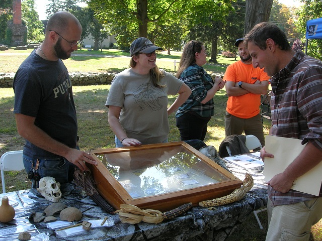 October 5, 2024.  Unknown Participant, unknown participant, Stephanie Scialo, 
                                         and Jordan Tabolt (ref image 20) and an unknown participant at the Archaeological & Historical Services, (AHS) Inc. table.