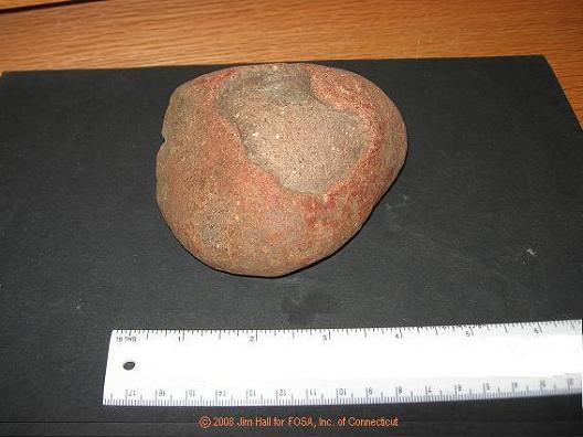 This is a fire-cracked hearthstone of basalt material. The large flake that is spalled from its outer surface was caused by excessive heat.