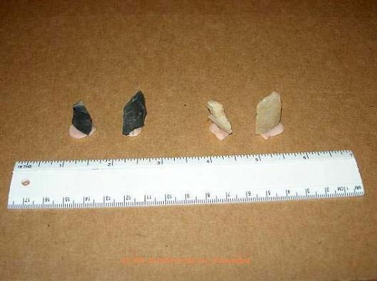 These are flakes and/or chips of flint (the dark material) and quartz. These are a by-product of stone tool manufacturing. The term 'debitage' is applied to this type of material.